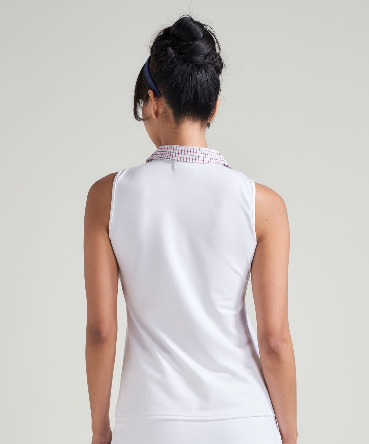 Back view of woman tennis athlete in white women's tank top with accented trim collar in red, white, and blue.