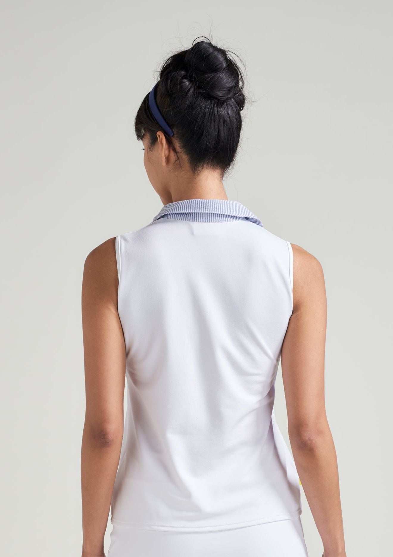 Back view of woman tennis athlete in white women's tank top with accented trim collar in blue seersucker.