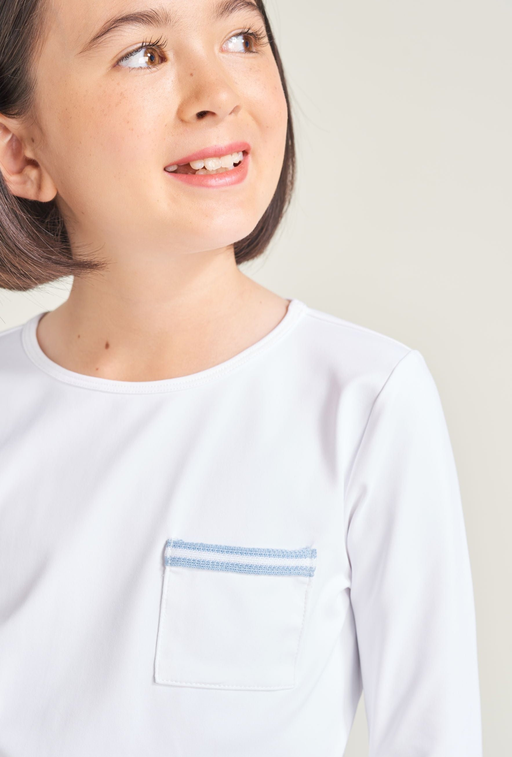 Detail picture of youth girl tennis player wearing white tennis t-shirt with blue and white trim on shirt pocket.