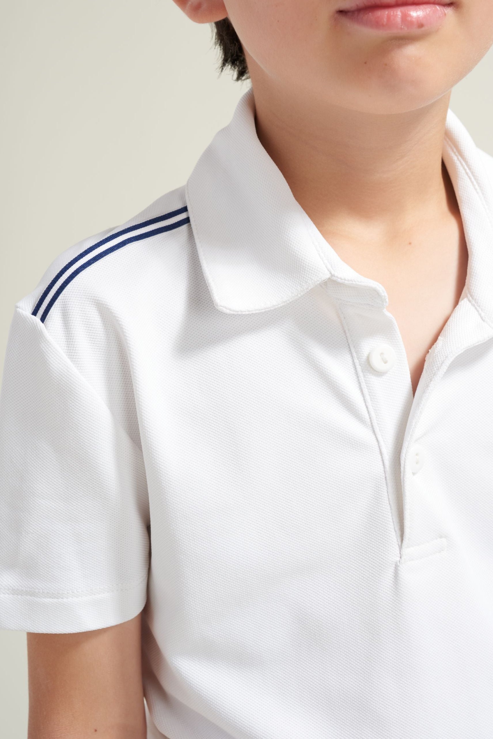 Boys' tennis athlete wearing a white polo tennis shirt with navy and white trim along shoulders.
