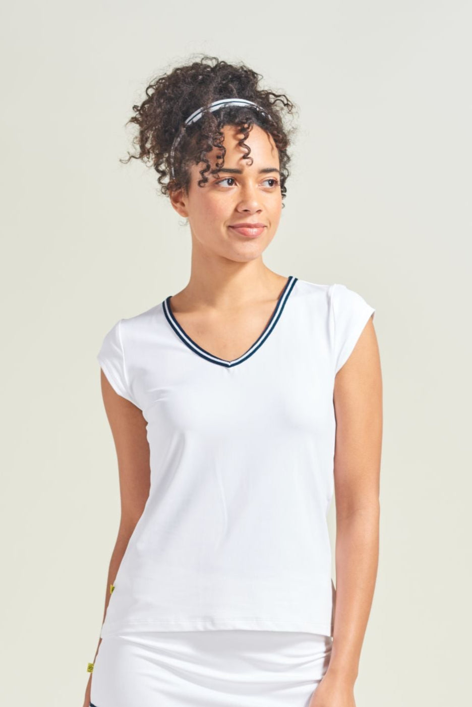 A women's tennis player wearing a white tennis t-shirt with navy and white knitted trim along the neckline.