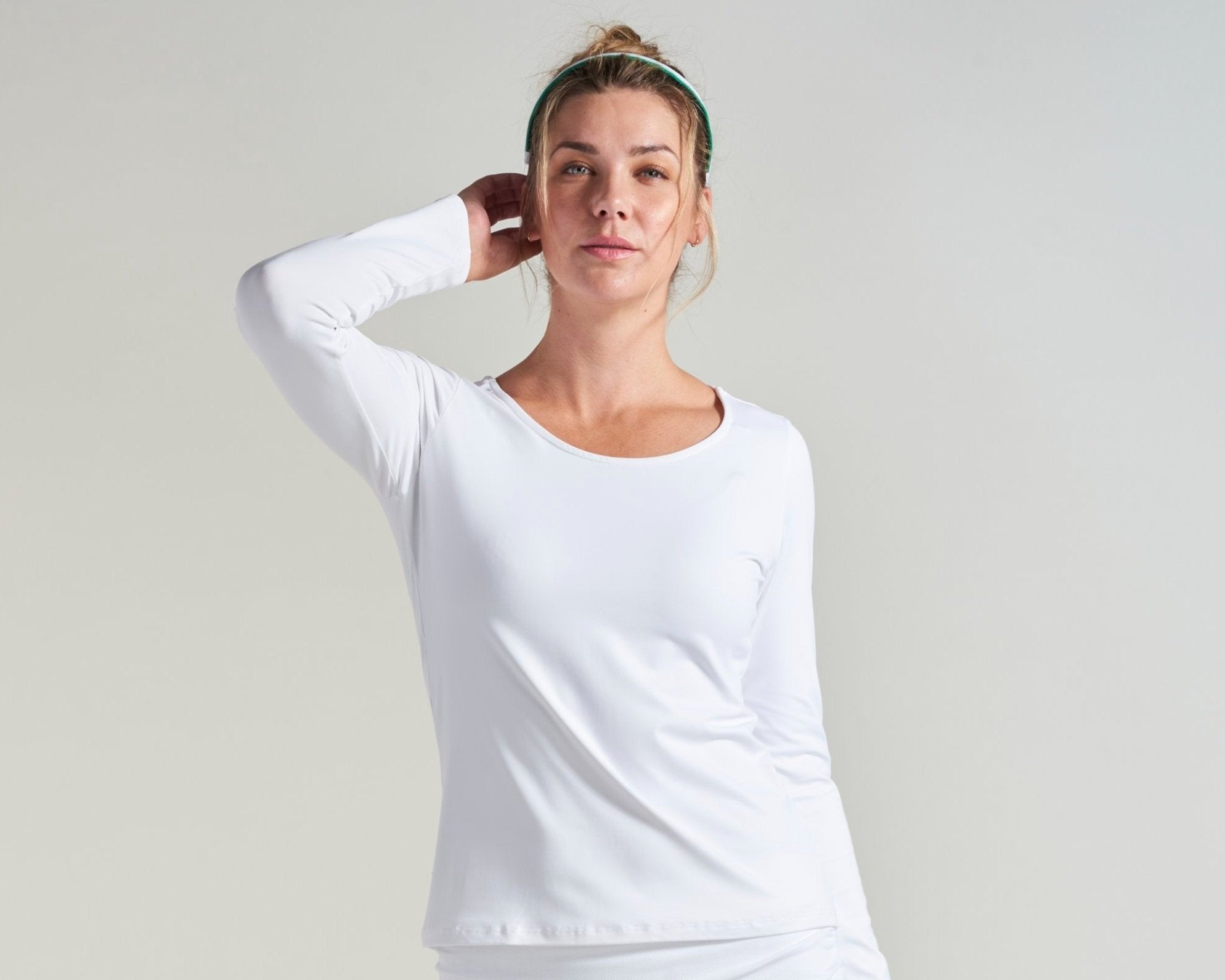 Women's tennis athlete wearing all white tennis long sleeve shirt.