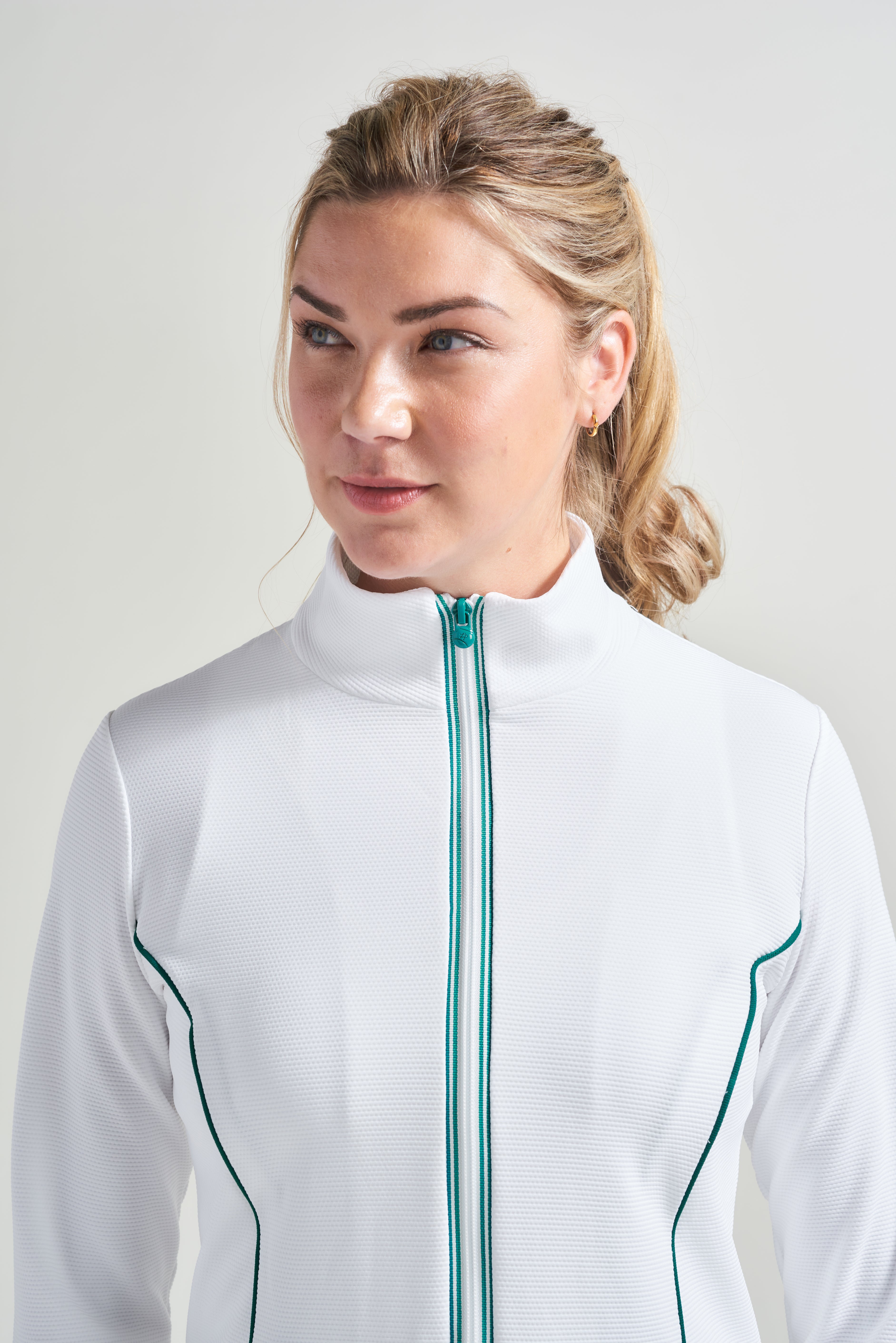Detail view of white tennis jacket with green accent trim and green detail piping