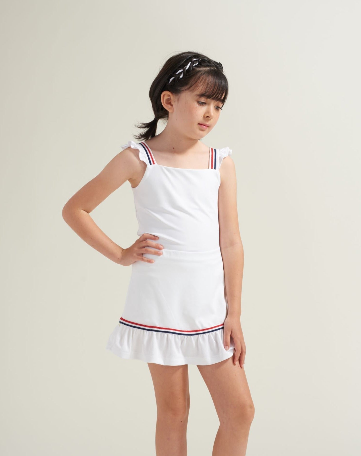 Kids tennis clothes in all white with red and blue accents.