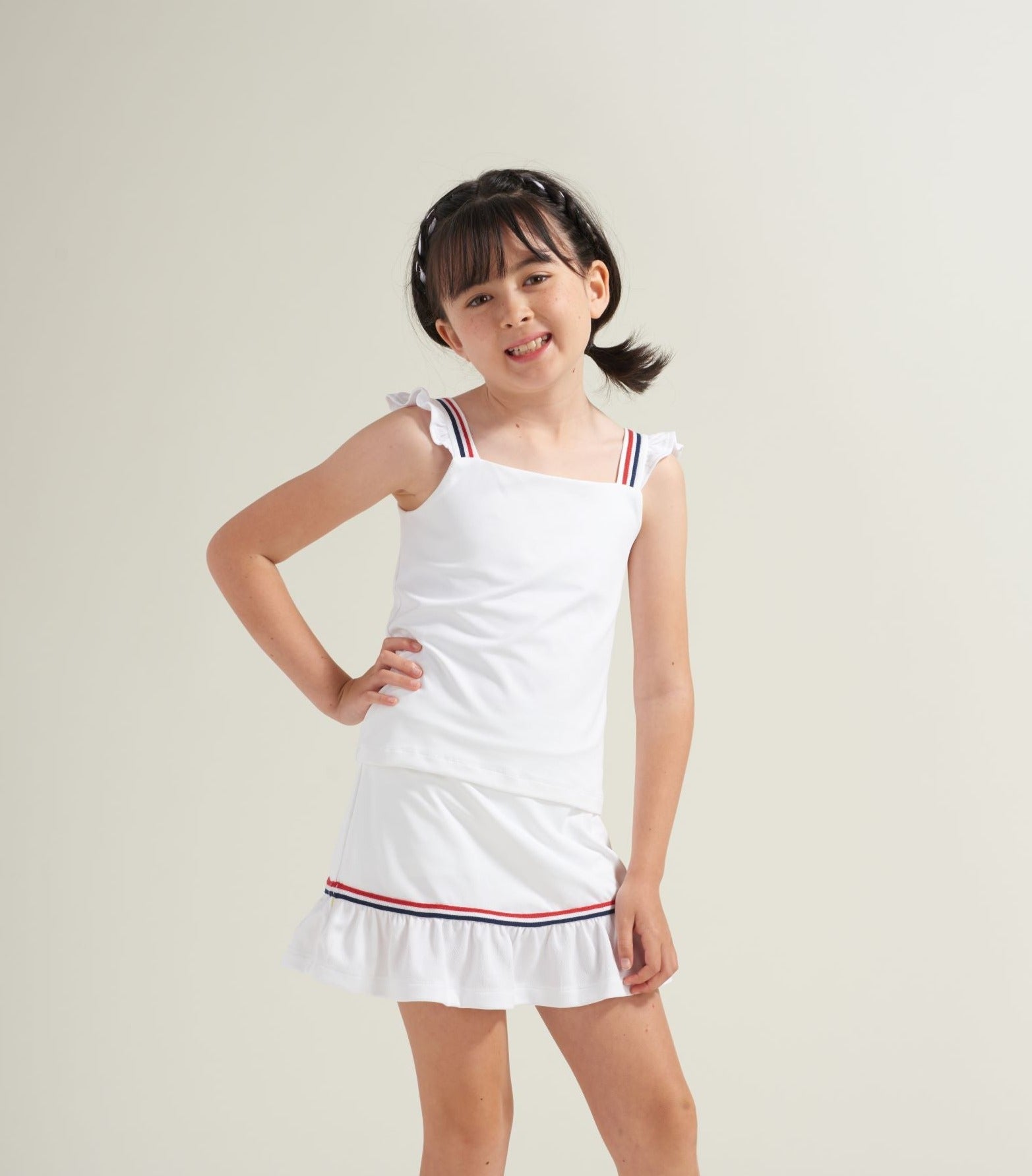 Kids white tennis apparel with red and navy accent trim.