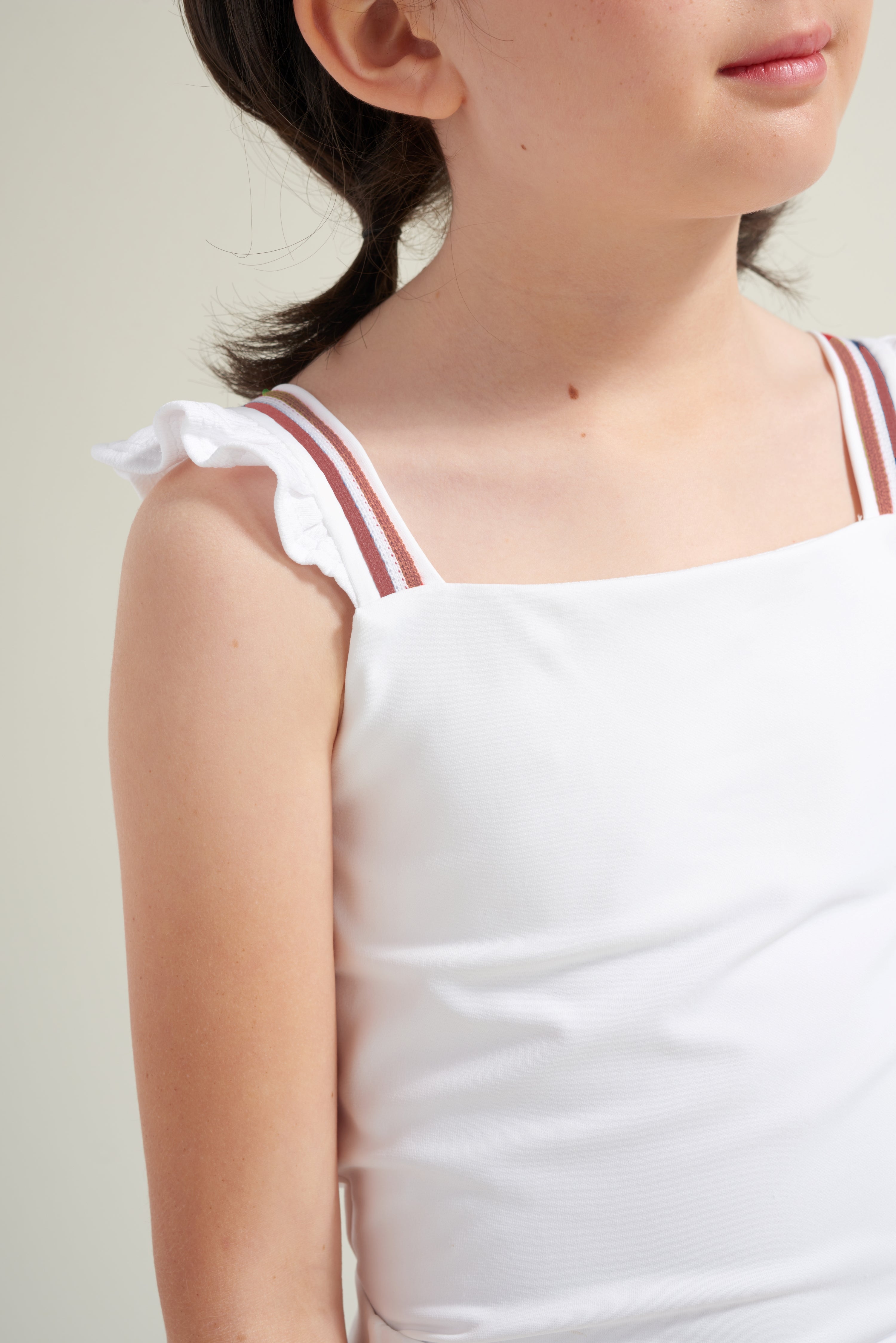 Detail view of white tennis tank top for girls with red accent trim on straps.