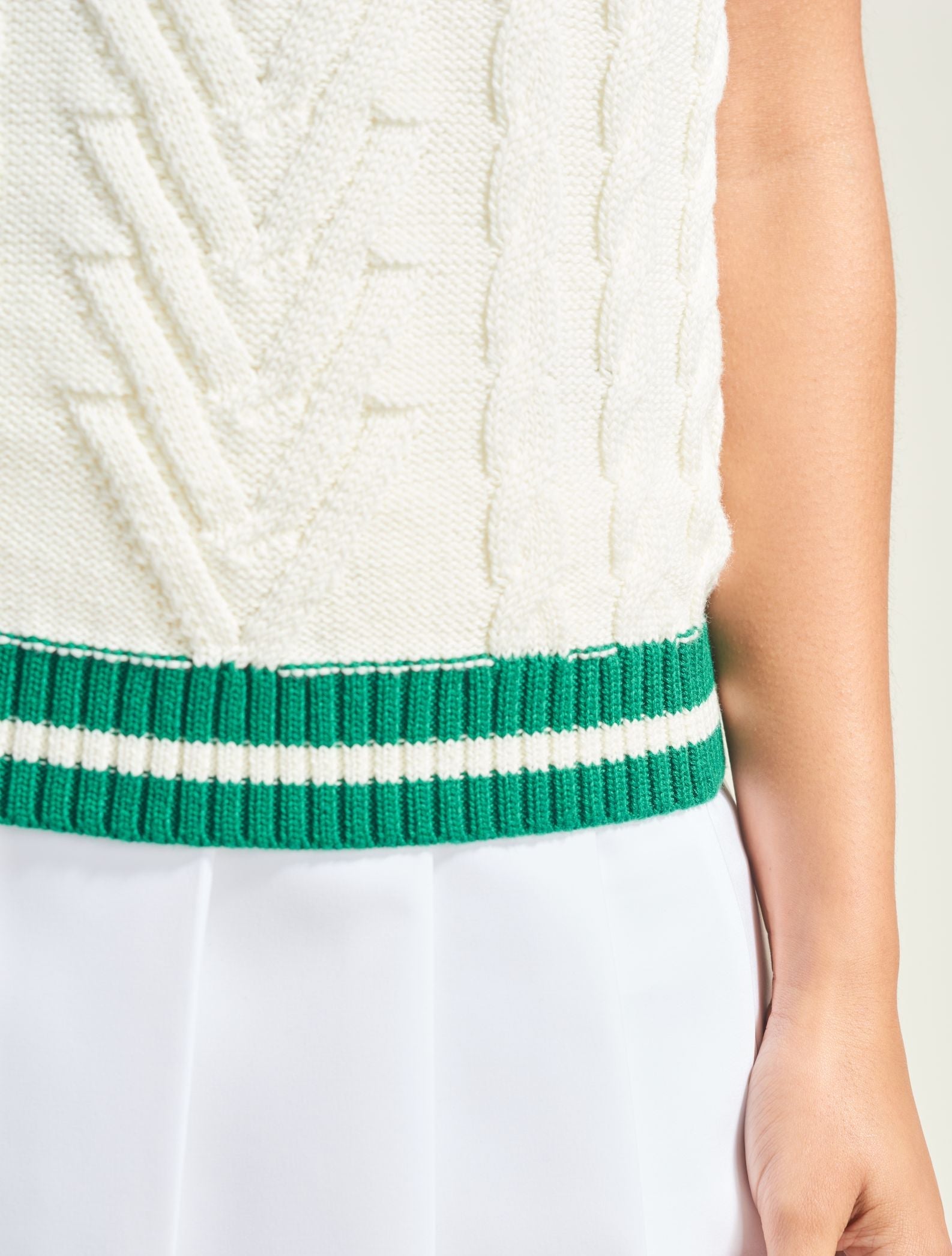 White dress with green and white striped waistband on a plain background