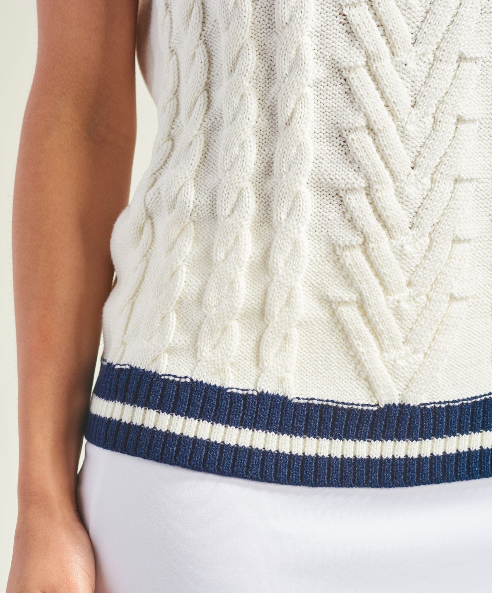 White cable knit sleeveless top with navy trim on a plain background