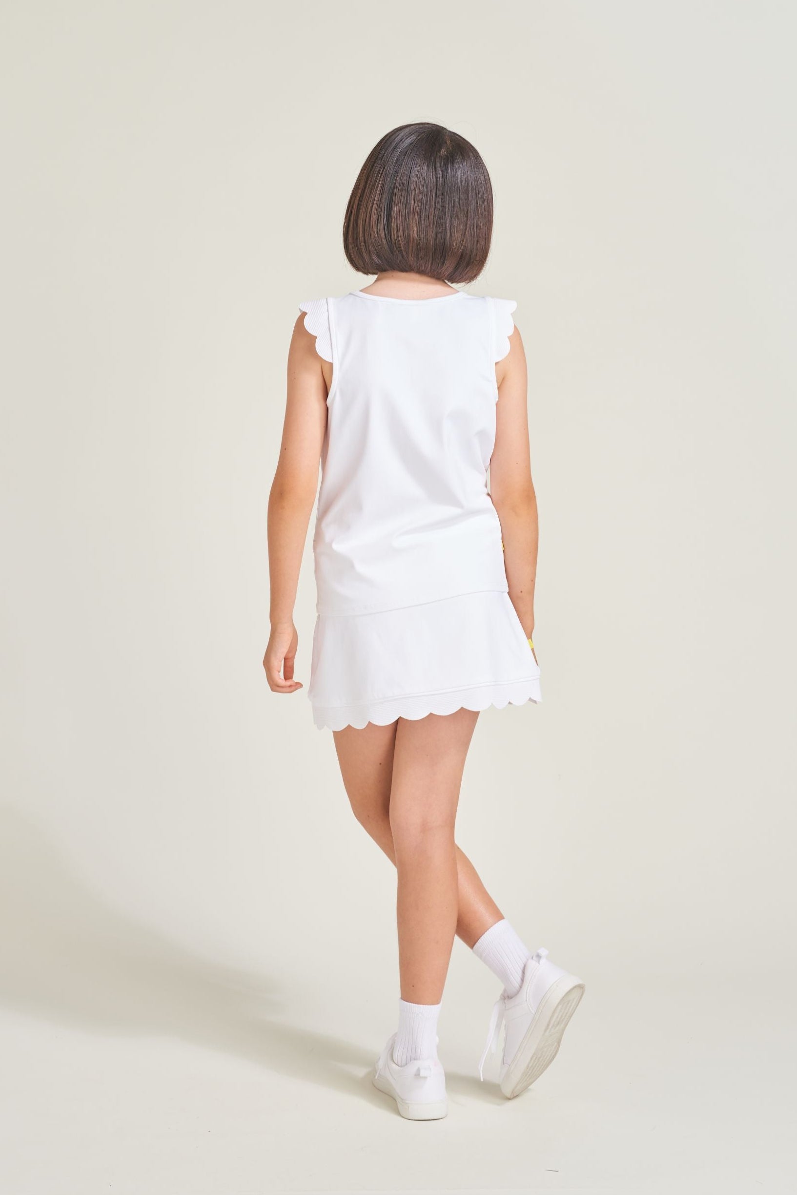 Back view of tennis athlete wearing all white skort for girls.