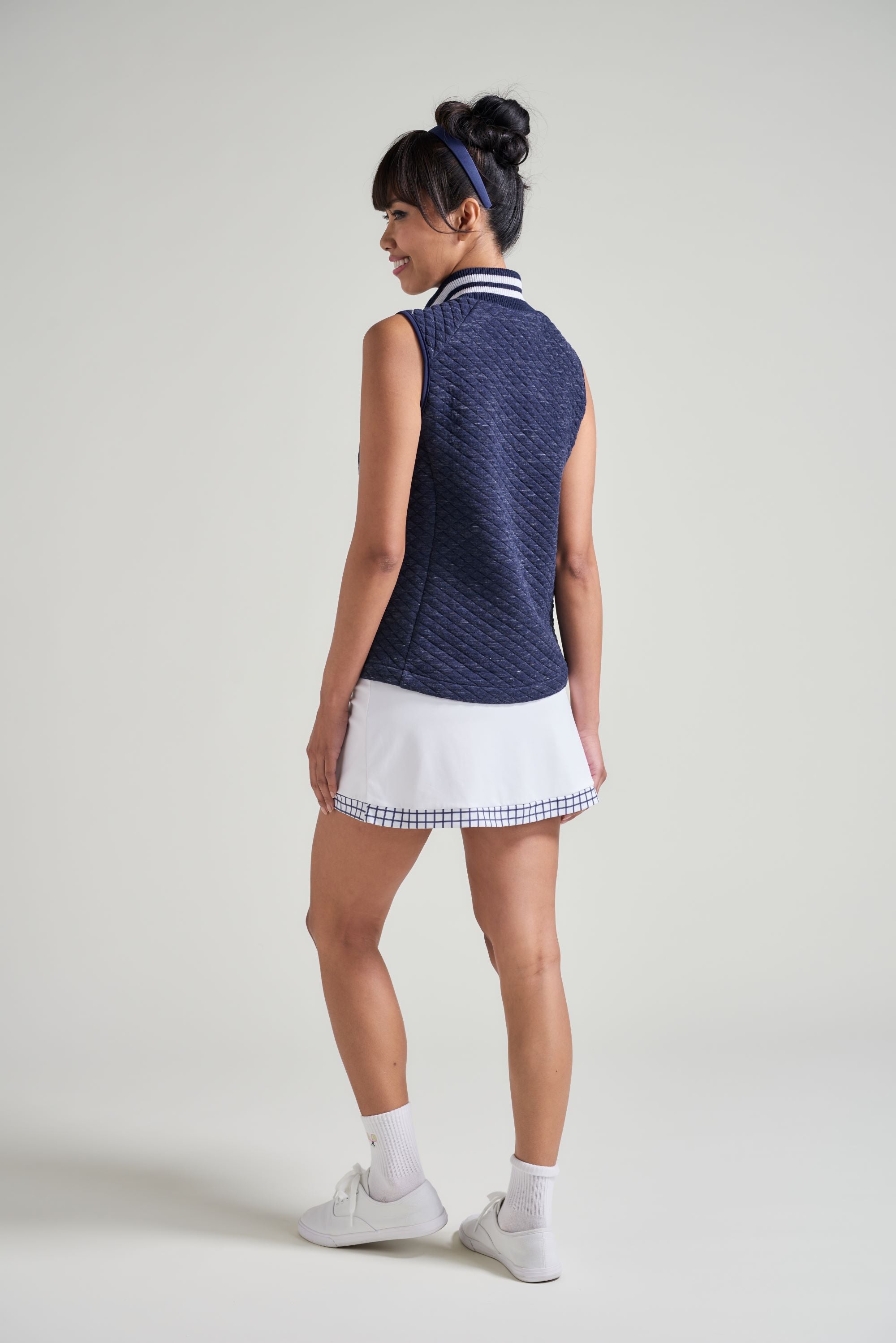 Back view of woman tennis player in workout warm up vest for women in tennis.