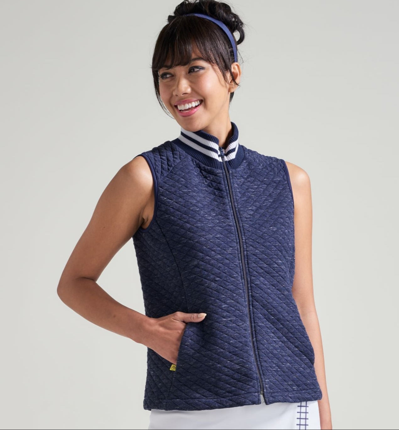 Woman tennis athlete in navy tennis warm up vest.