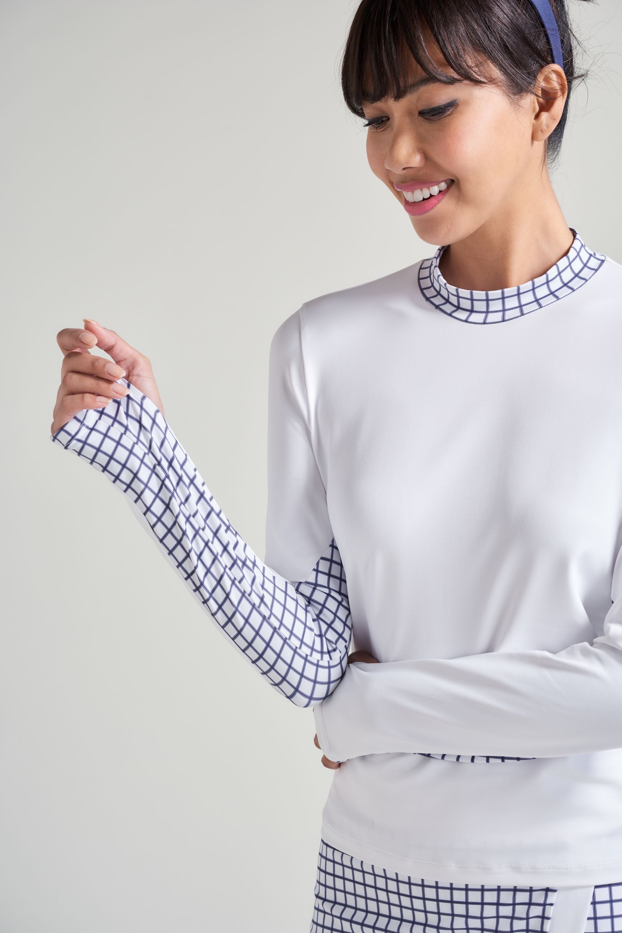 Women's tennis athlete wearing tennis long sleeve shirt with contrast fabric on sleeve and mock neck.