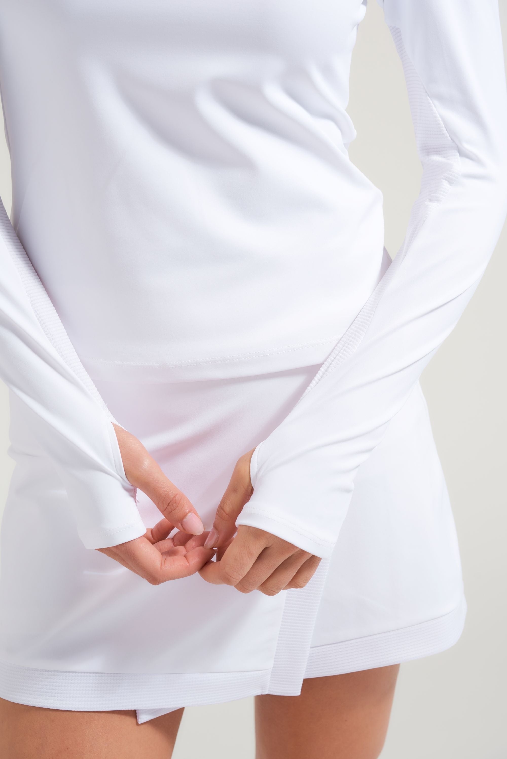 Close up view of white tennis t-shirt with thumb hole opening on sleeves and contrast fabric.