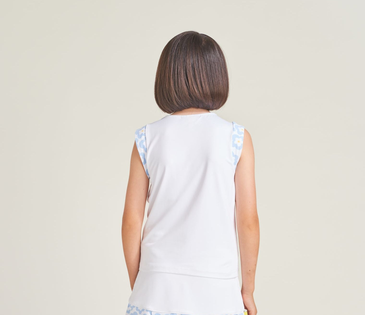 Back view of youth girl tennis athlete wearing white girls workout shirt with cap sleeves.