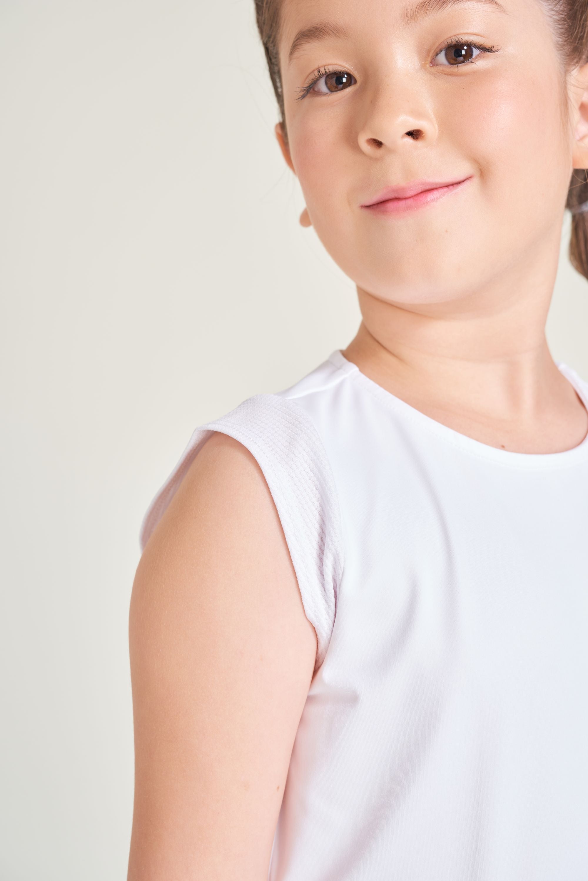 Detail view of youth girl athlete wearing white tennis t-shirt with cap sleeves.