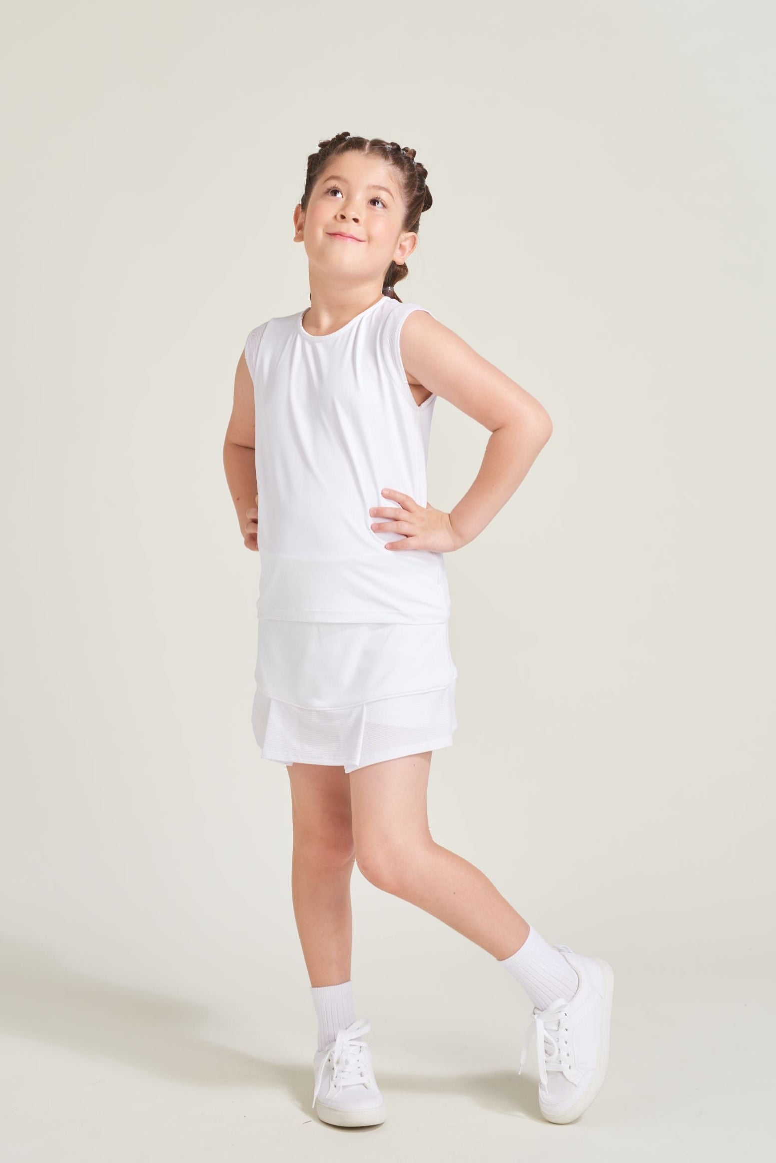 Kids' tennis athlete wearing white tennis matching set with white mesh accents.