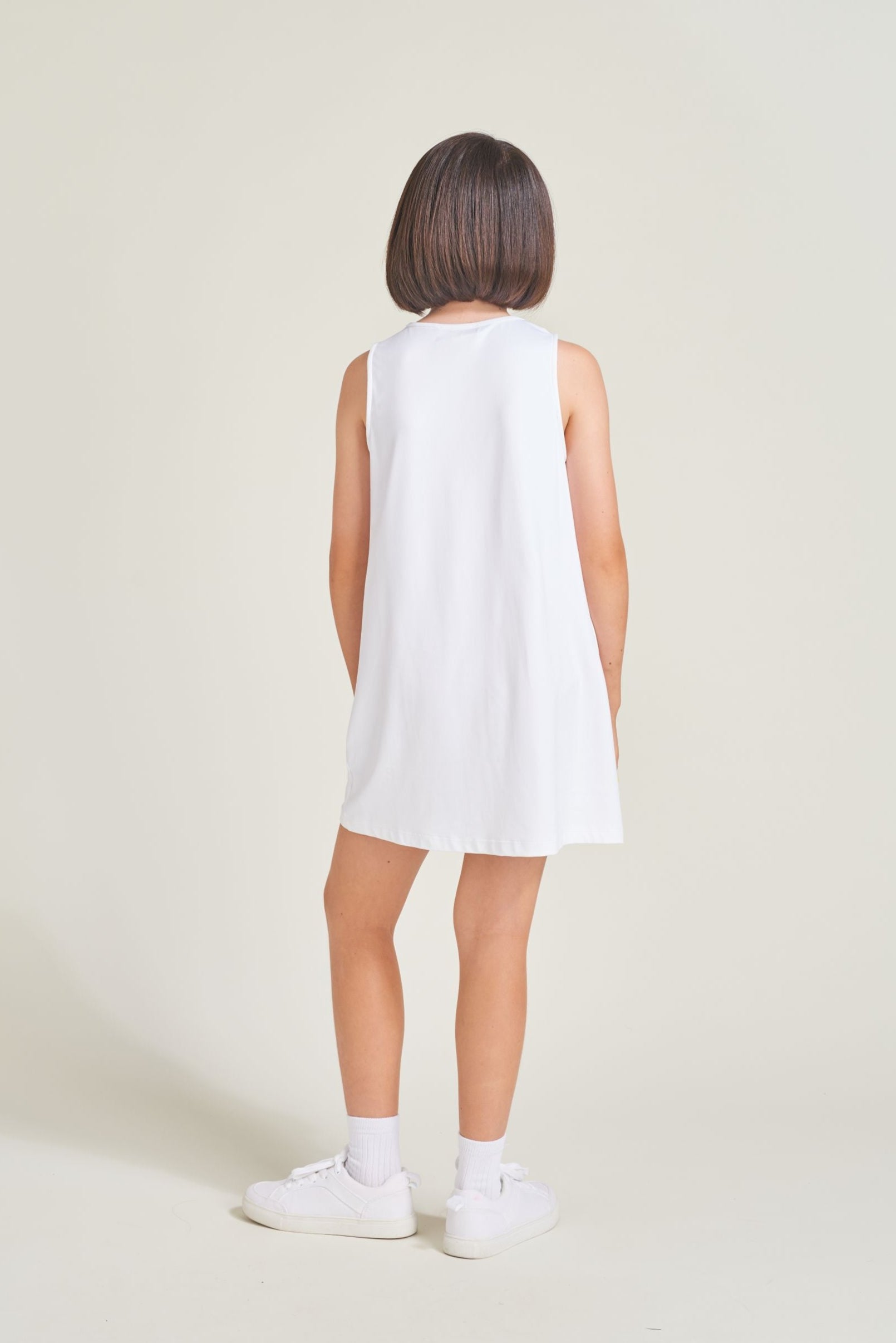 Back view of kids tennis player wearing all white tennis dress for girls.