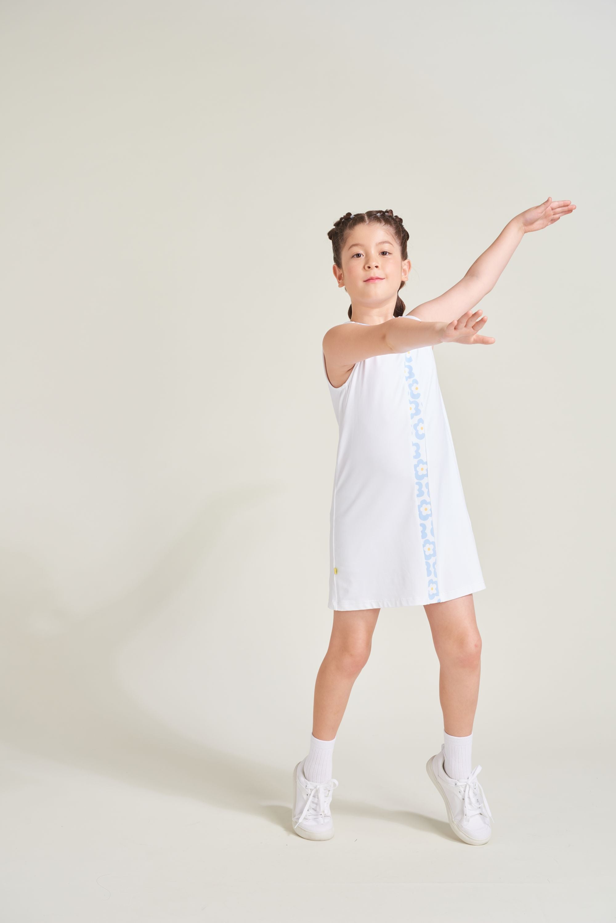 Youth athlete wearing all white tennis dress for girls with flower print accents.