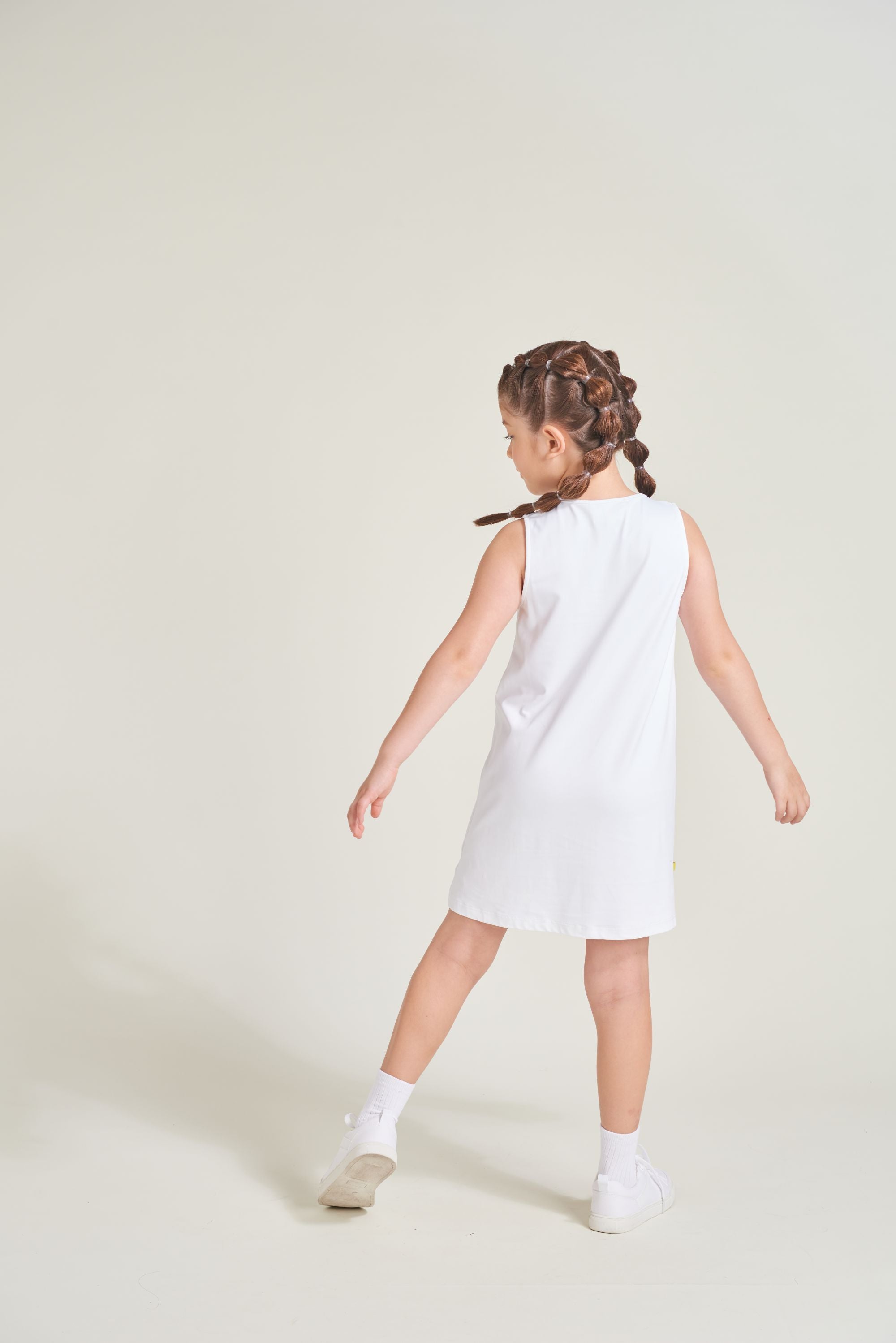 Back view of all white tennis dress on youth girl.