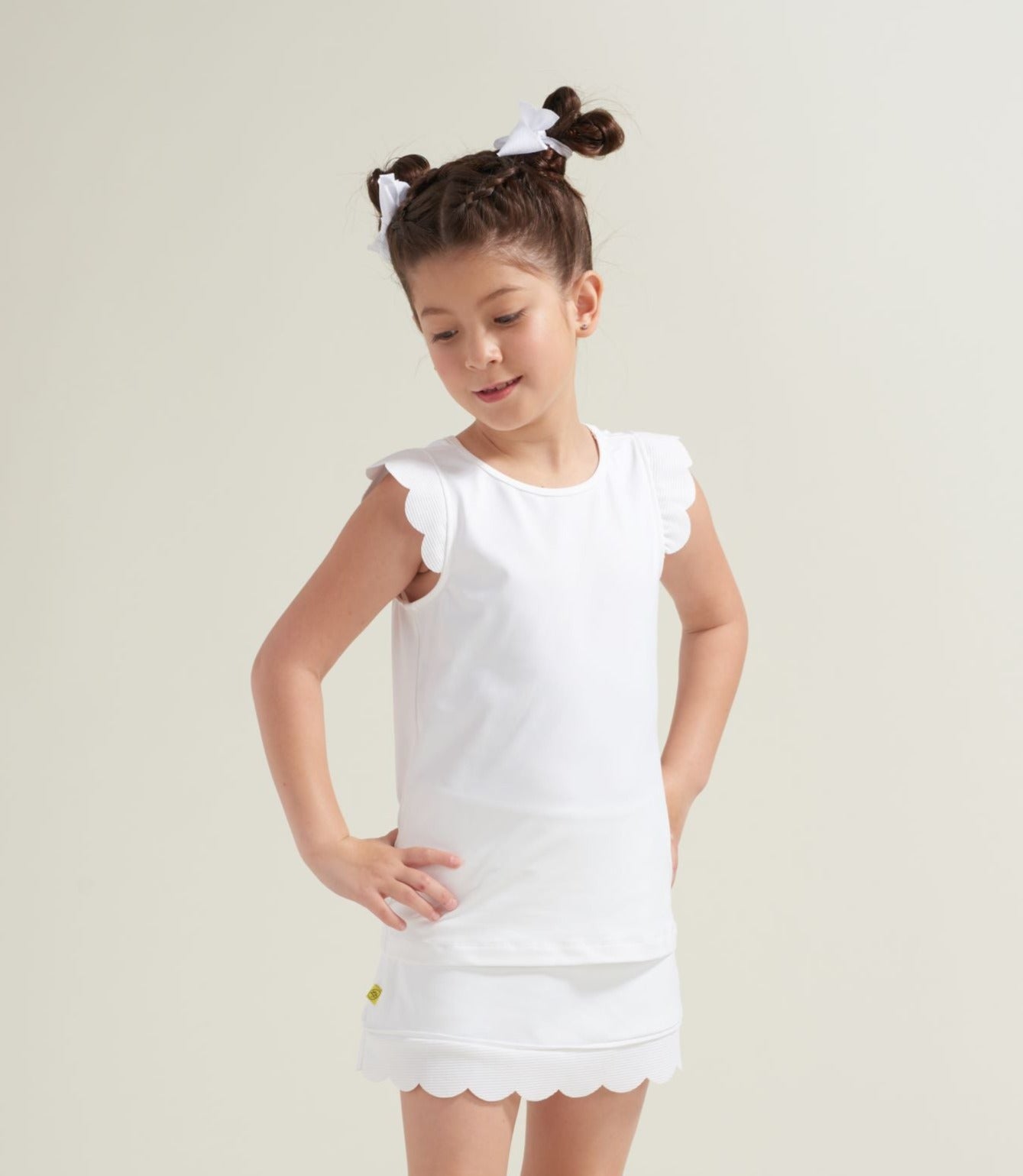Girl tennis player wearing all white tennis tank top with white scalloped edges.