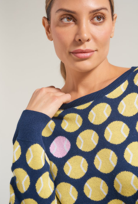 Detail picture of women's tennis athlete wearing navy women's tennis knit sweater. Sweater has yellow and pink accents.