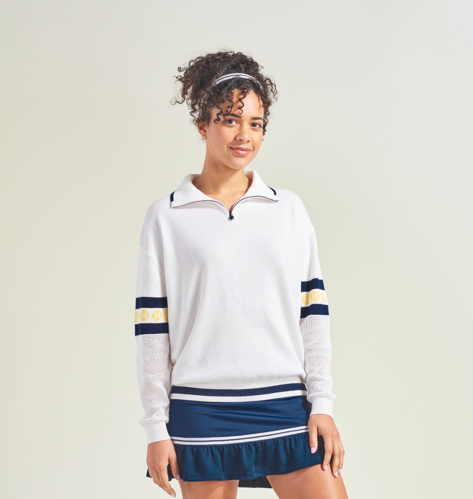 Person wearing a white and navy tennis outfit on a plain background