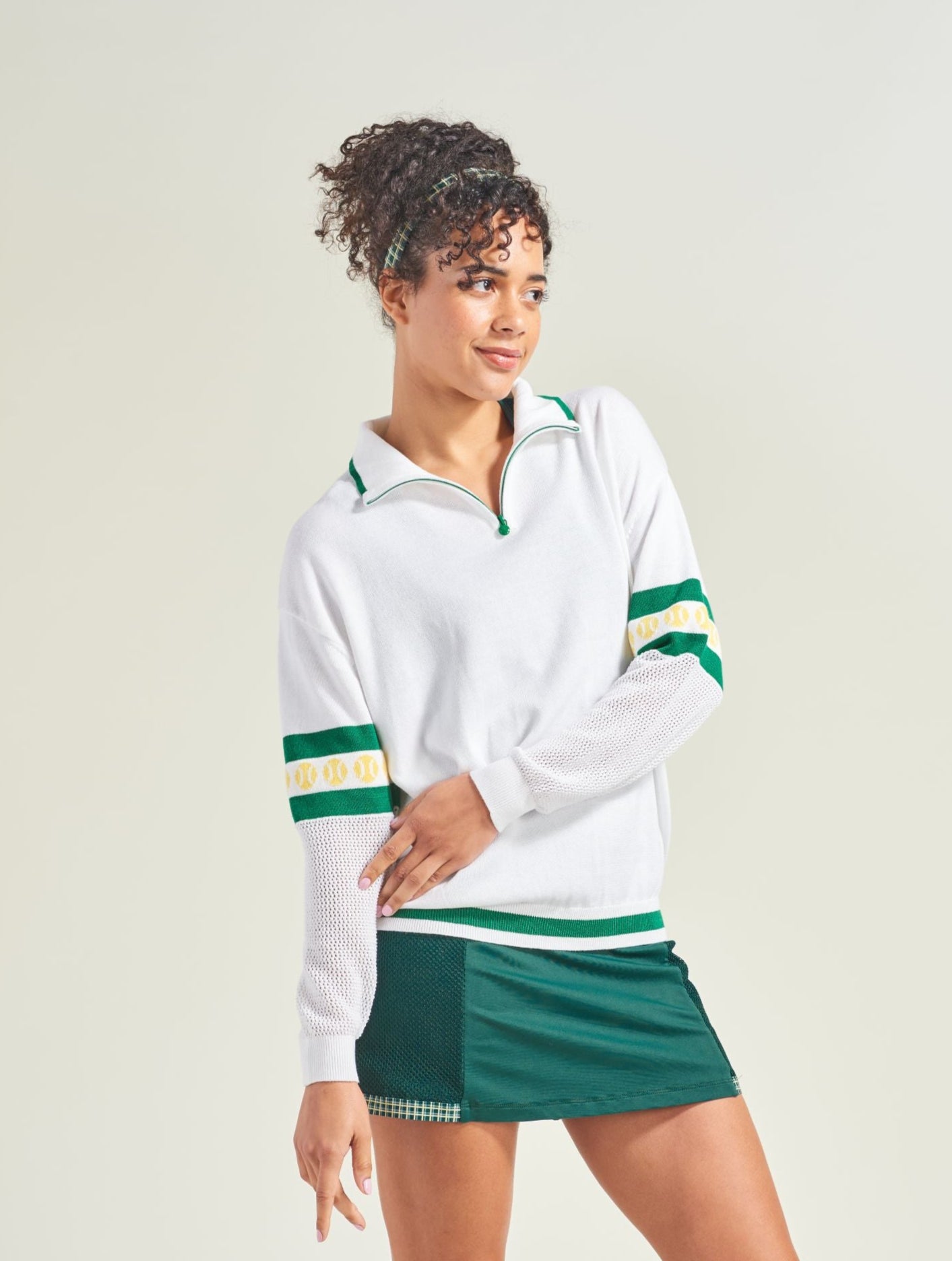 Woman wearing a white and green sports outfit on a plain background