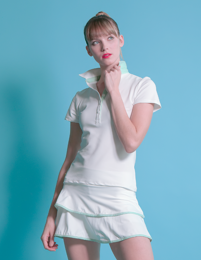 Female tennis player with white tennis polo shirt with green pop of color on collar and neckline.