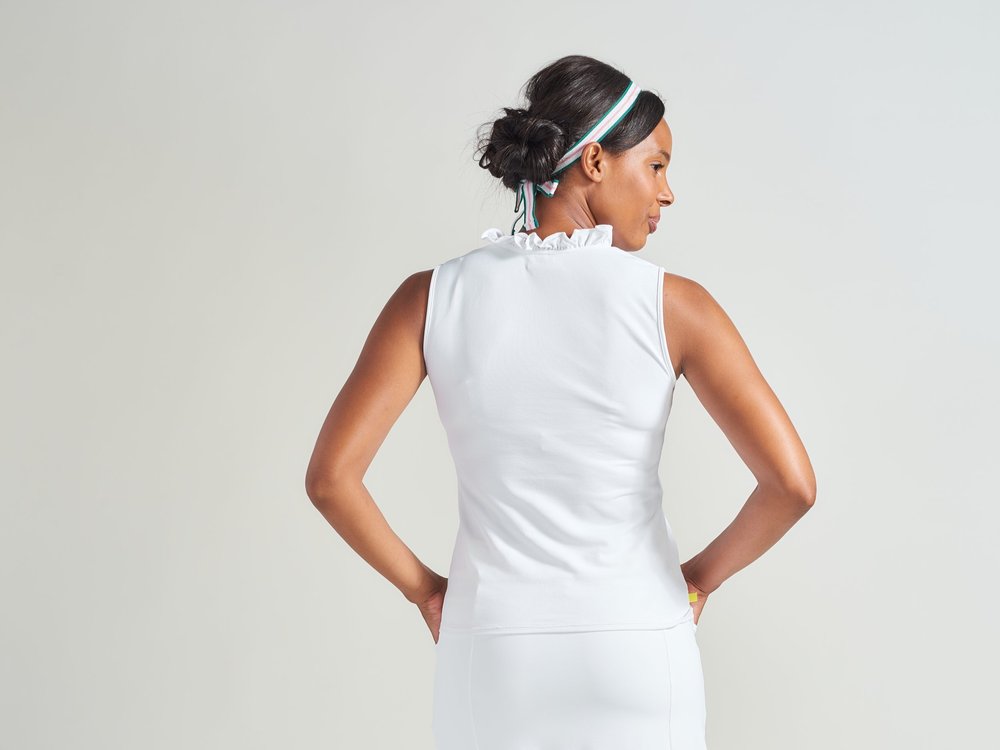 Back view of woman tennis player in all white tennis tank top with white tennis skort.