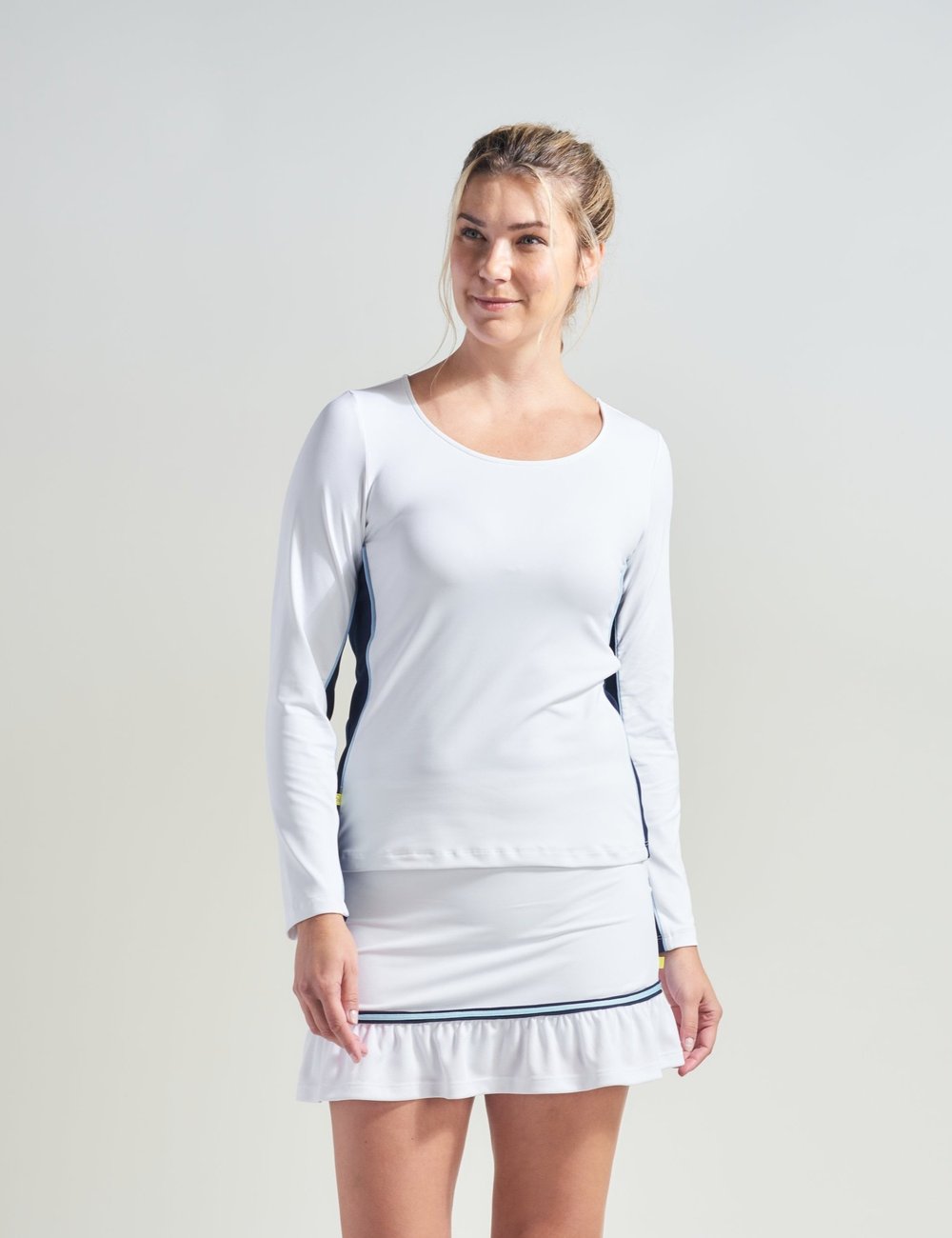 Tennis player wearing white tennis t-shirt for women with navy blue color blocking. Woman athlete is also wearing white tennis skort with navy and blue trim.