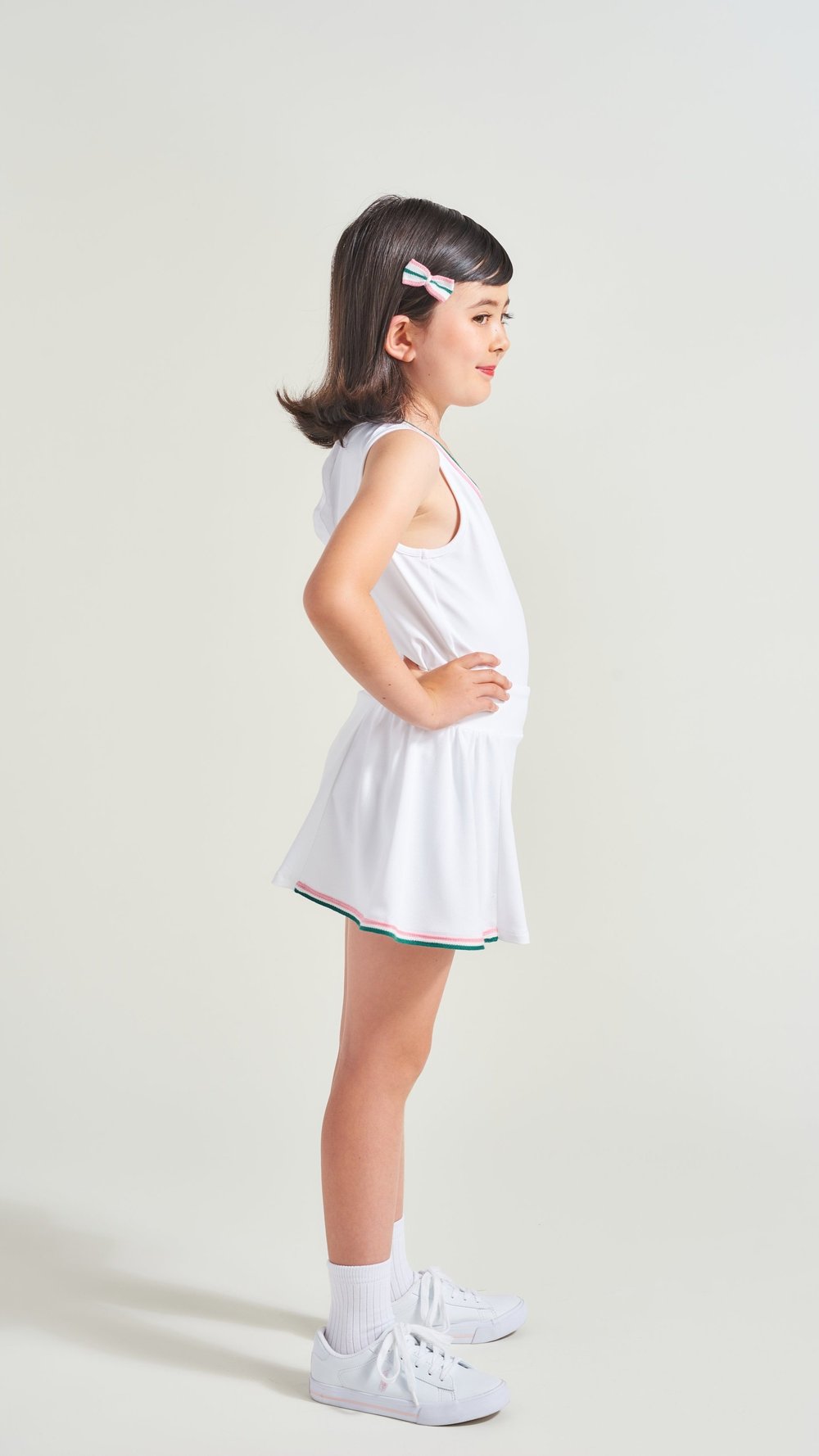 Side view of white side ruffle tennis skort with pink and green trim along hemline for kids
