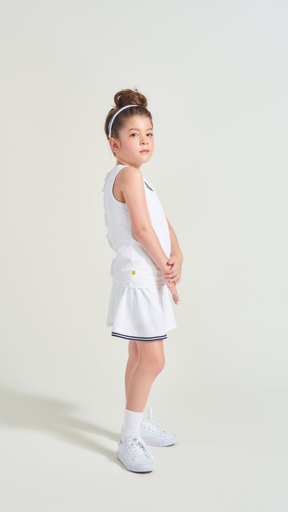 Side view of white tennis clothes for kids with navy accent trim