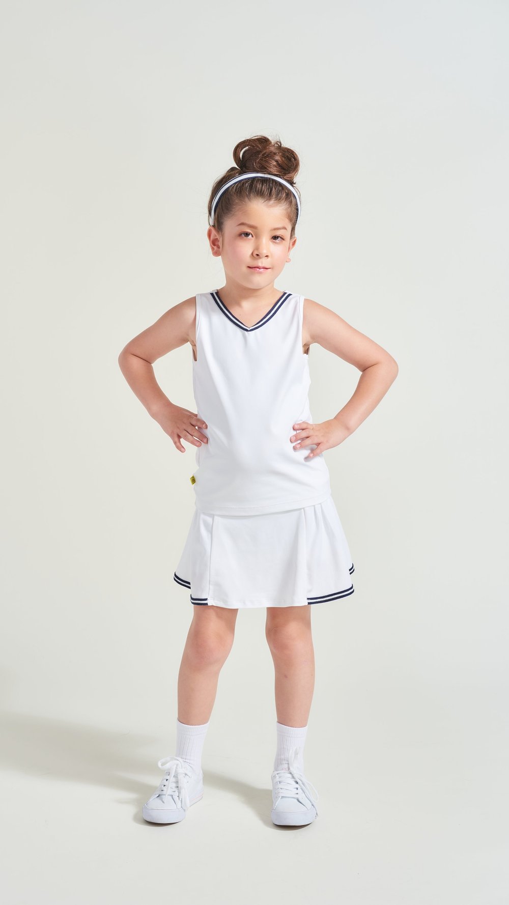 Kids tennis apparel in all white with navy trim along neckline and hem