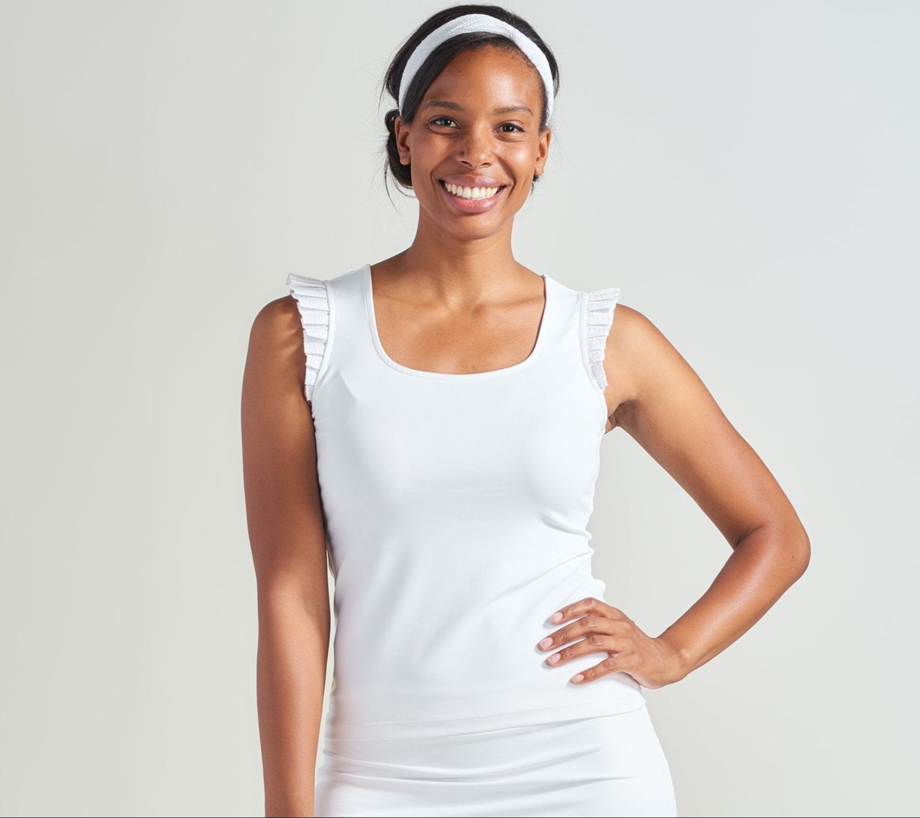 Woman tennis athlete wearing white tennis tank with white seersucker pleats.