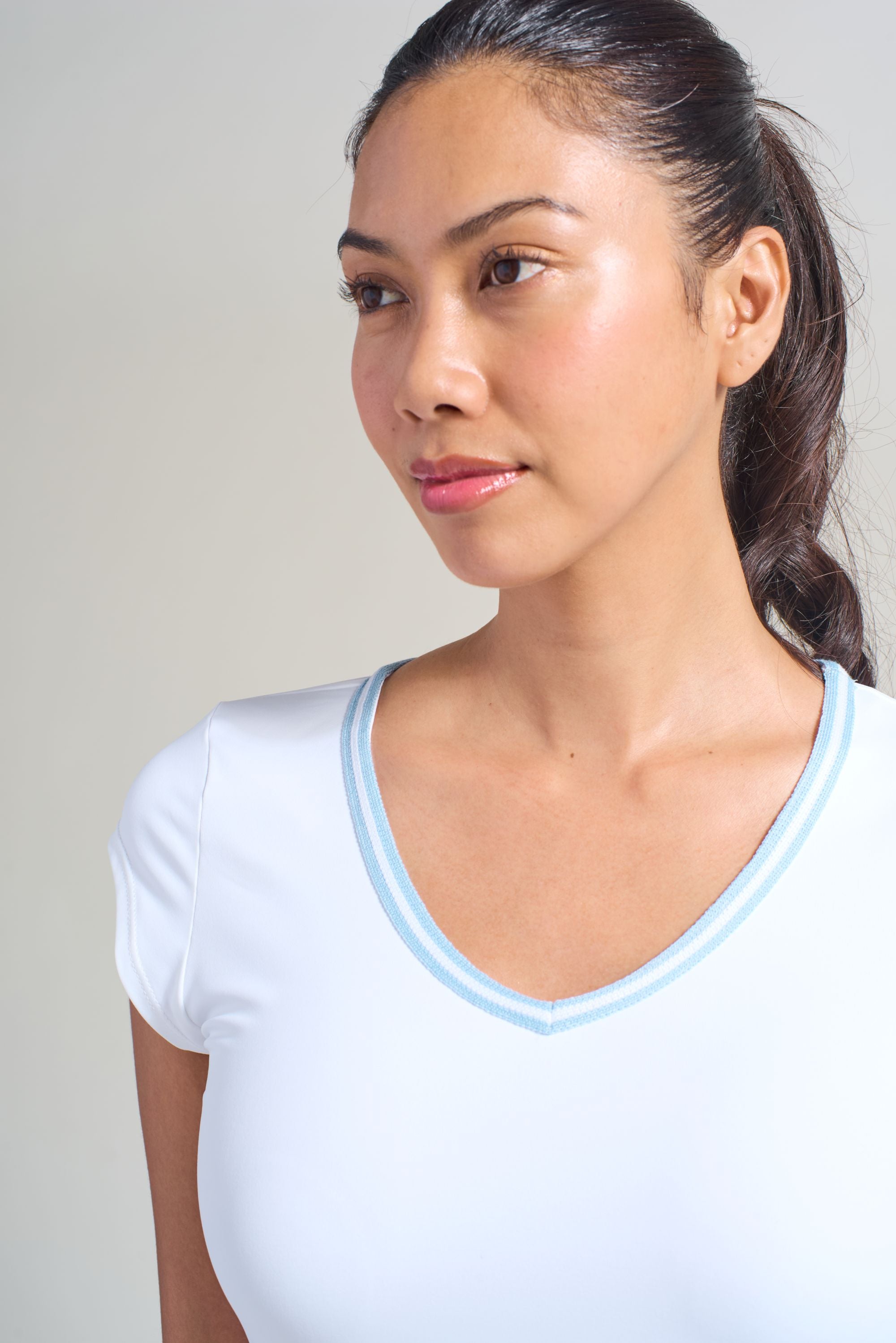 Women's white activewear shirt with light blue trim around v-neckline. 