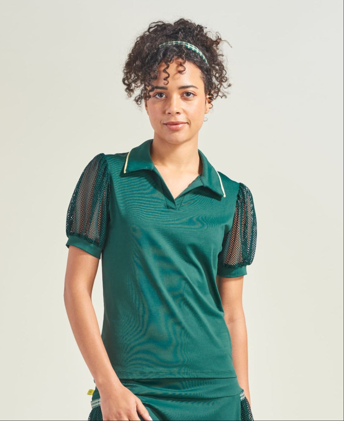 Woman wearing a green dress with black mesh panels on a white background
