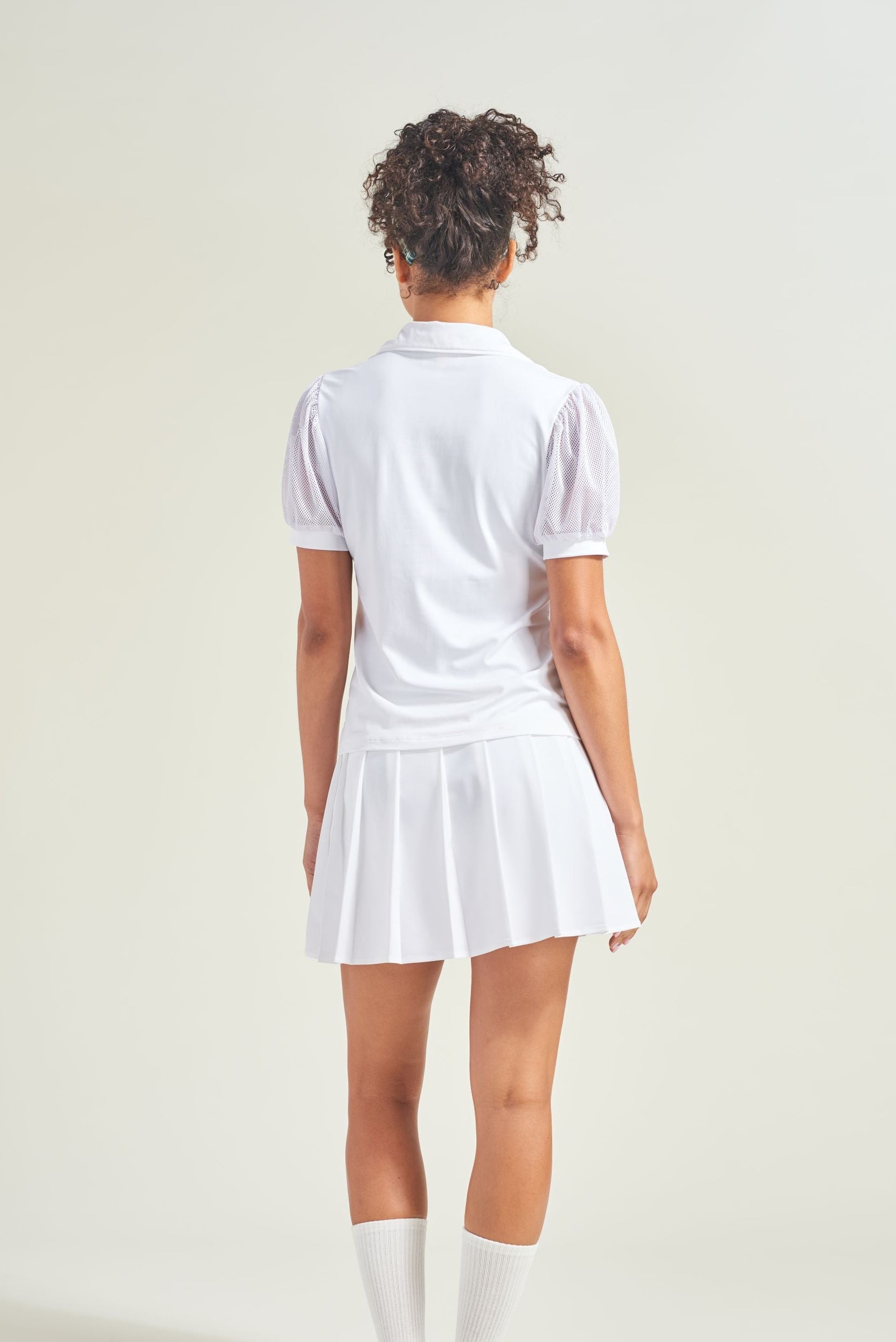 Person wearing a white tennis outfit on a plain background