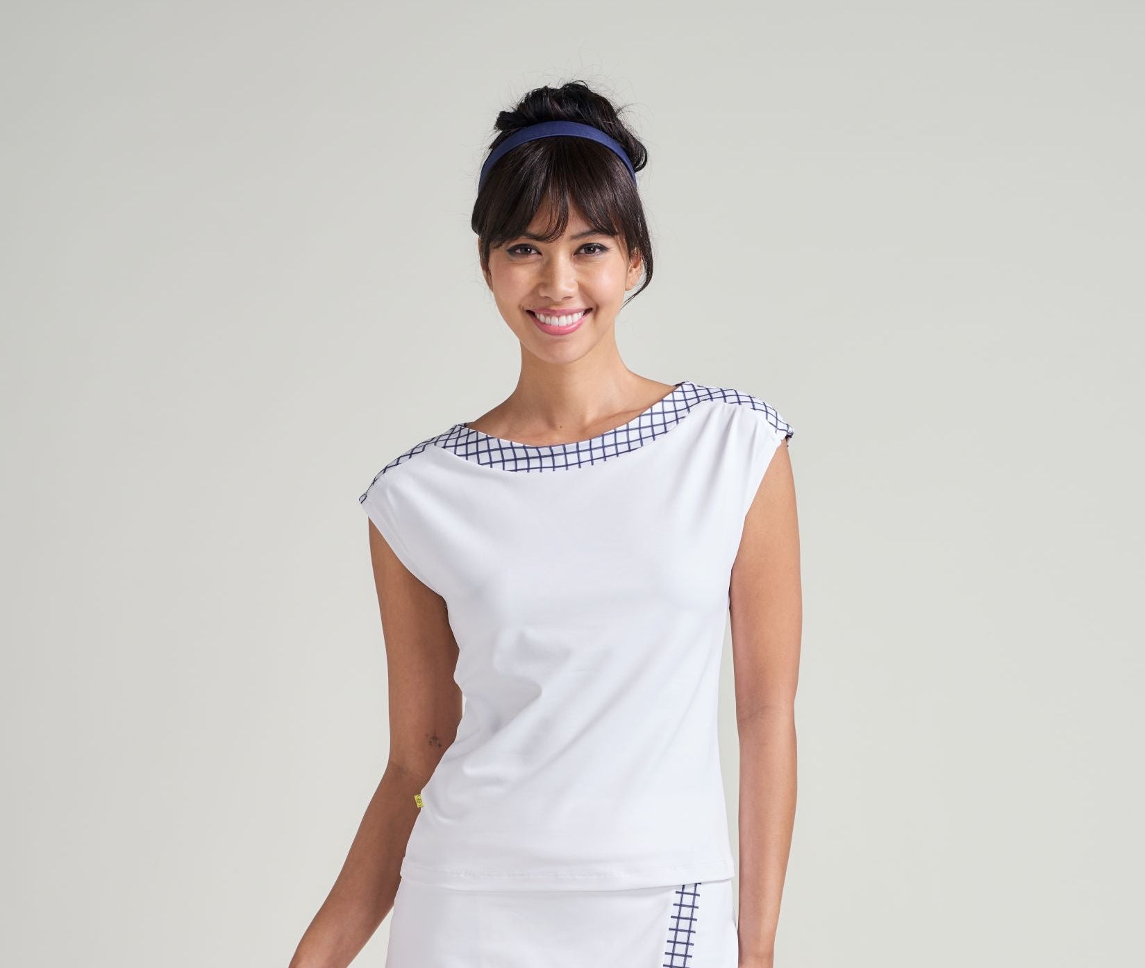 Woman wearing a white outfit with a checkered pattern on a plain background