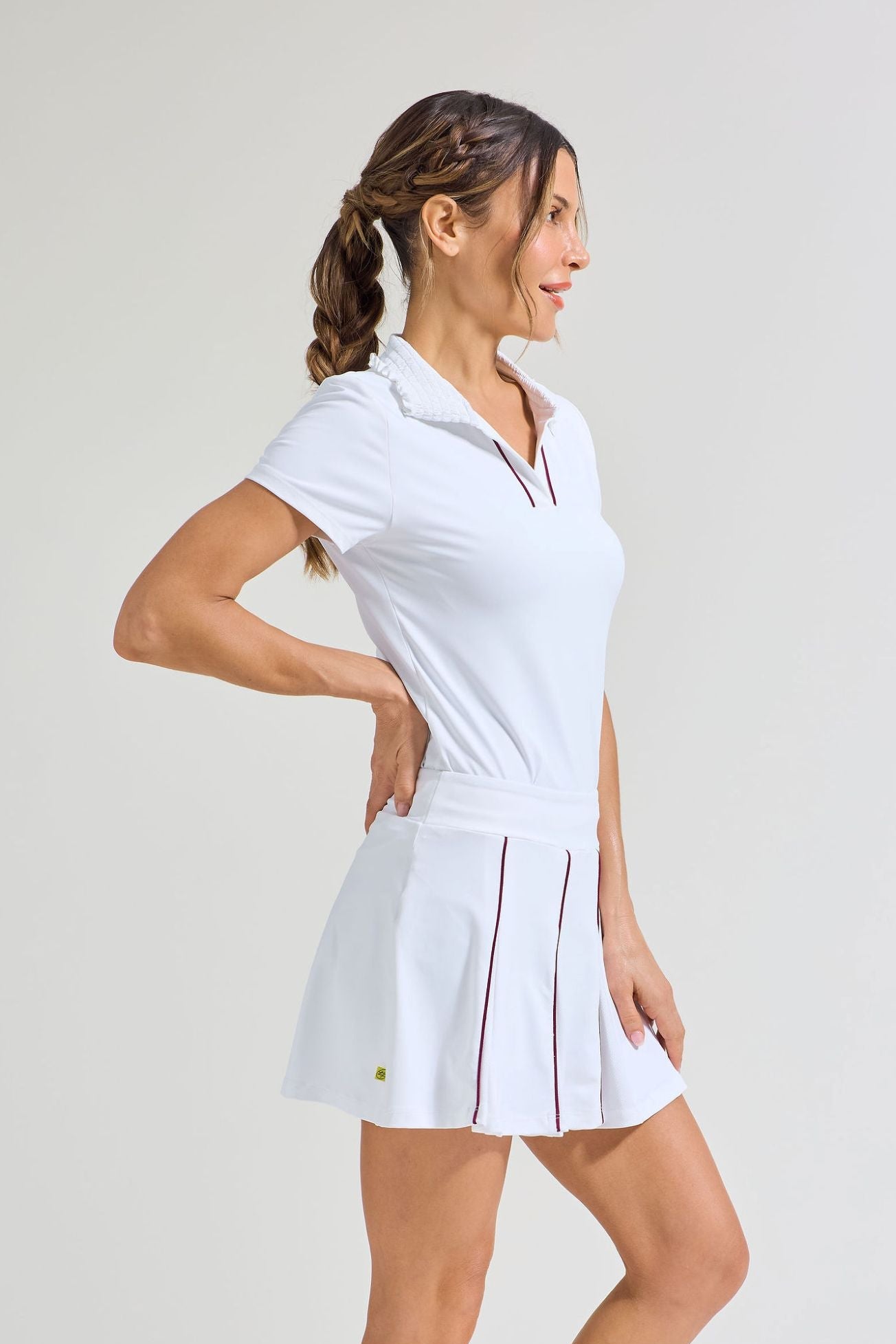 Side view of pleated tennis skort for women with all white tennis t-shirt with smocked collar. 